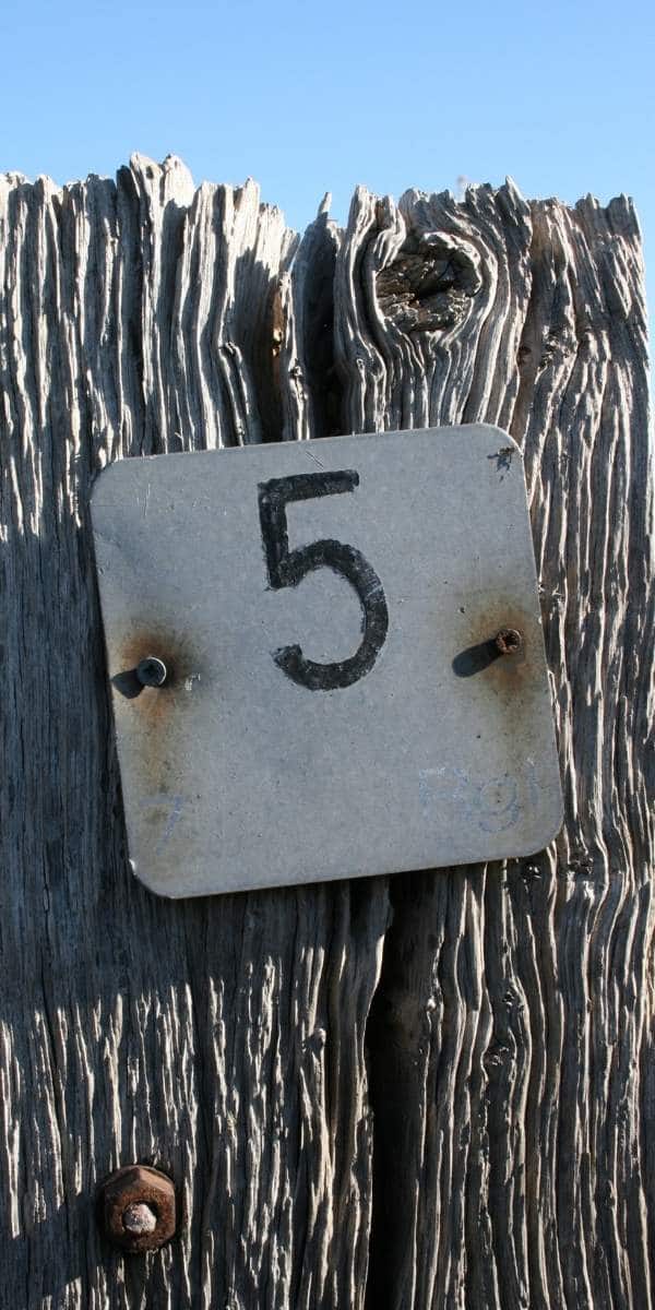 the number 5 on a metal plate nailed to a fence